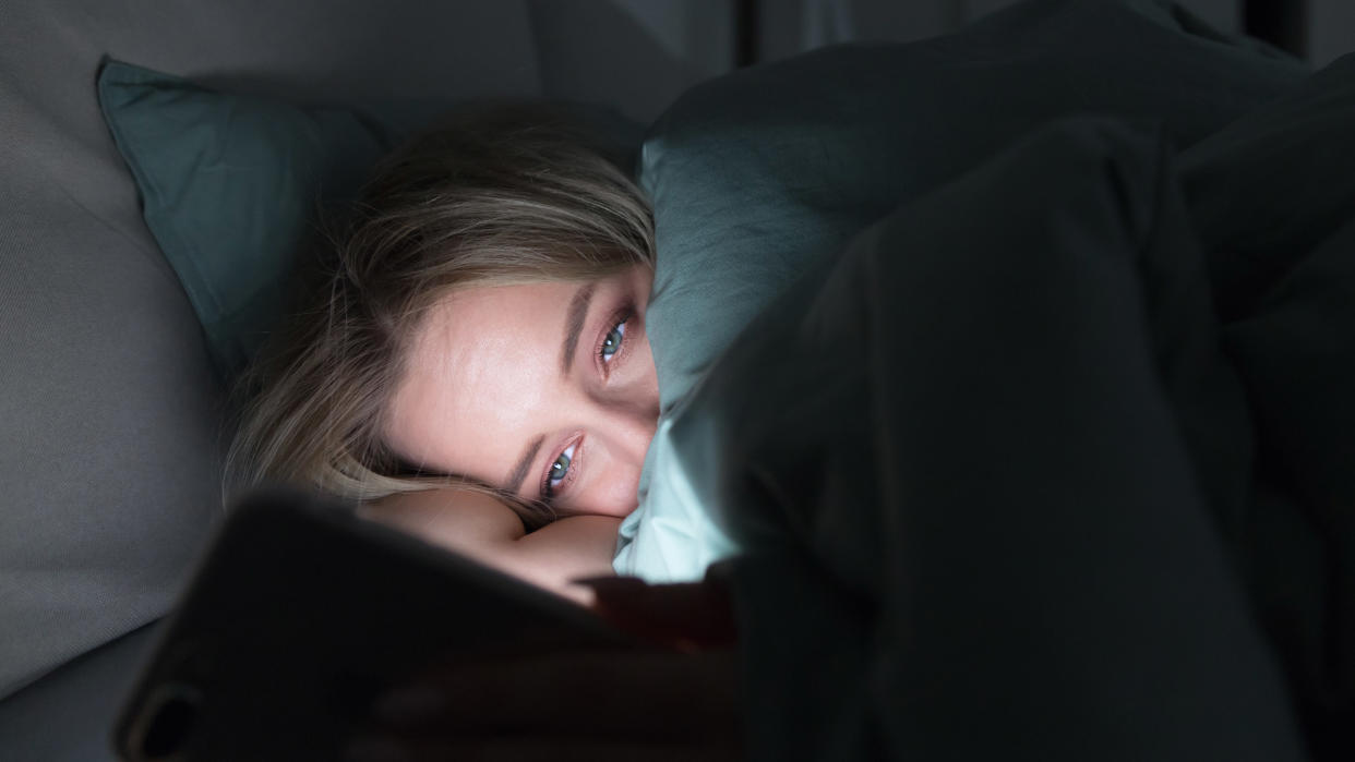  A phone being used by a woman in bed. 