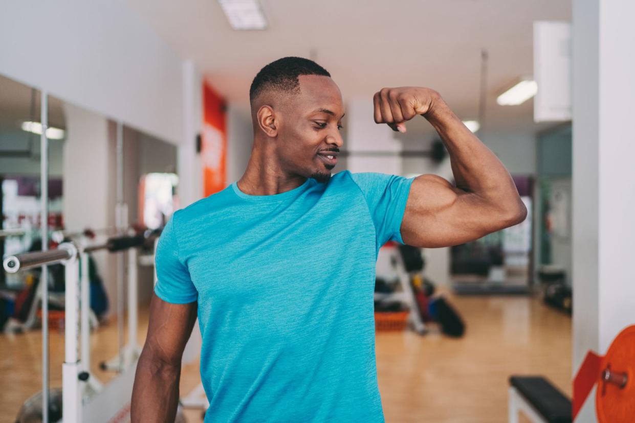 Young man in the gym checking progress of his biceps