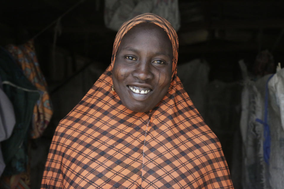 In this photo taken on Monday, Feb. 18, 2019, Fati Umar, a woman displaced by Islamist extremist smiles as her photo is taken at Malkohi camp in Yola, Nigeria. Fati Umar of Gwoza, said she was unable to bury her husband after fleeing a 2014 Boko Haram attack that came while she was cultivating her garden, and for days she hid in the bush with her children. Fati speaks in the makeshift camp for internally displaced people that she shares with hundreds who all have their own story to tell, and who all have more important issues than the upcoming presidential election. (AP Photo/ Sunday Alamba)