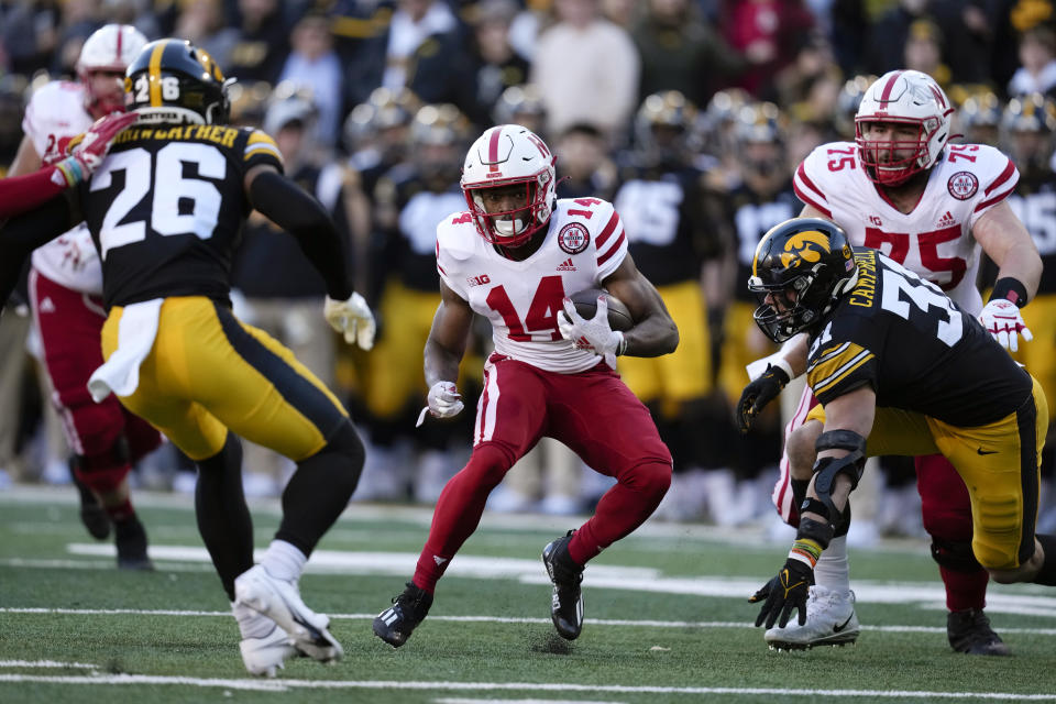 Nebraska running back Rahmir Johnson (14) runs from Iowa defensive back Kaevon Merriweather (26) and linebacker Jack Campbell (31) during the first half of an NCAA college football game, Friday, Nov. 25, 2022, in Iowa City, Iowa. (AP Photo/Charlie Neibergall)