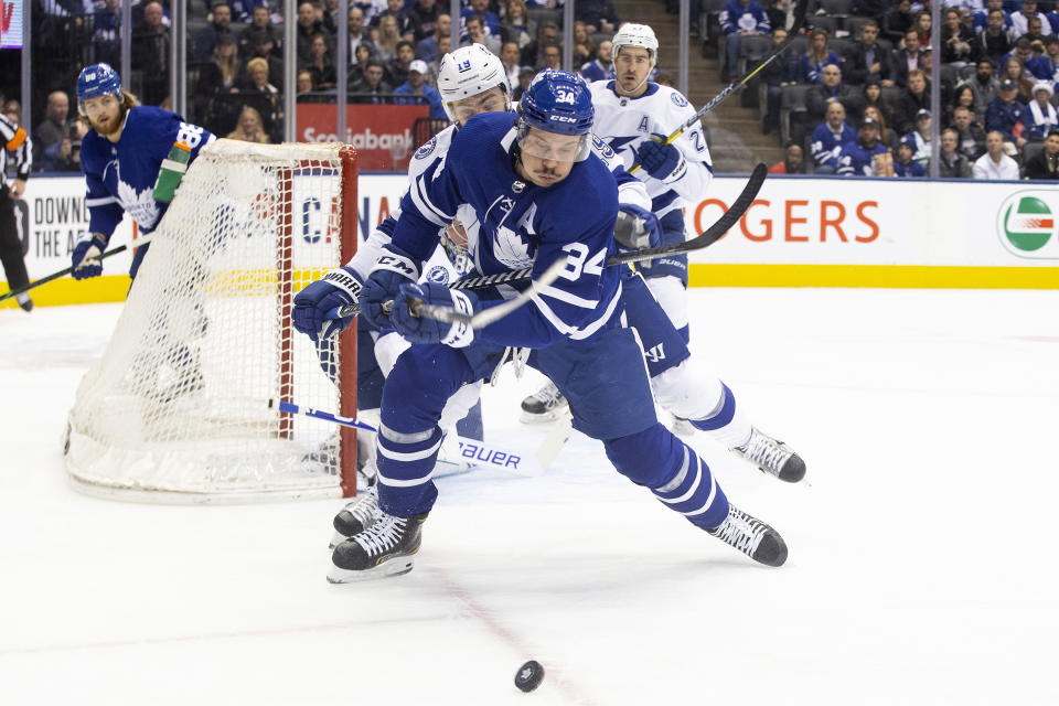 Toronto Maple Leafs center Auston Matthews (34) is hooked by Tampa Bay Lightning center Barclay Goodrow (19) during the first period of an NHL hockey game Tuesday, March 10, 2020, in Toronto. (Chris Young/The Canadian Press via AP)