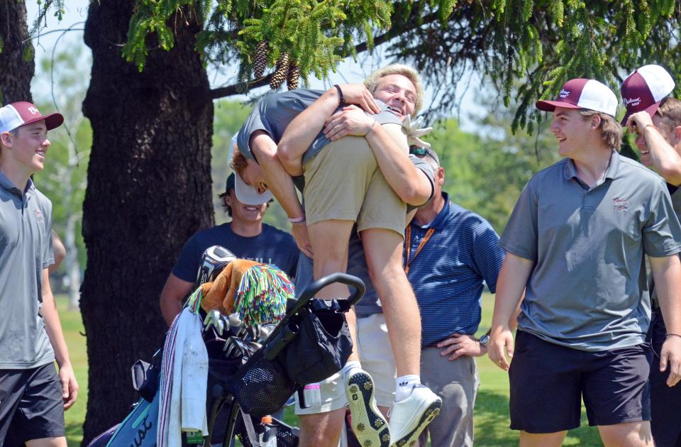 Charlevoix's Henry Herzog lifts teammate Hudson Vollmer as Rayder players gather to celebrate Vollmer's individual regional title and their own team regional title on Tuesday at Harbor Point Golf Club in Harbor Springs.