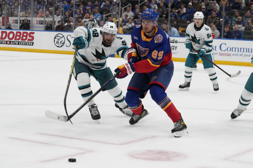St. Louis Blues' Pavel Buchnevich (89) and San Jose Sharks' Mario Ferraro (38) chase after a loose puck during the second period of an NHL hockey game Thursday, March 9, 2023, in St. Louis. (AP Photo/Jeff Roberson)