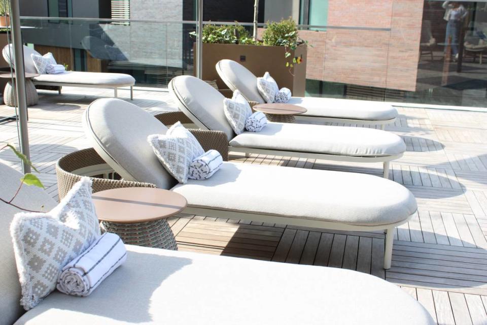 uxurious cabanas in rich wood accents lined the azure pool. Trendy gray benches wrapped around the interior of the cubicles. Matching loungers lined the length of the pool accented by blue throw pillows. On one end of the patio, the bar.