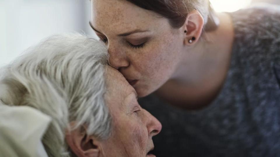 Una anciana recibe un beso en la frente