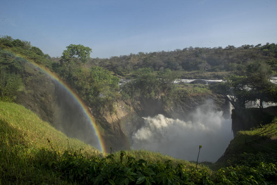 FILE - A rainbow forms in the mist at the top of the waterfalls in Murchison Falls National Park, northwest Uganda, on Feb. 22, 2020. Africa’s national parks, home to thousands of wildlife species are increasingly threatened by from below-average rainfall and new infrastructure projects, stressing habitats and the species that rely on them. Climate change and large-scale developments, including oil drilling and livestock grazing, are hampering conservation efforts in protected areas, several environmental experts say. (AP Photo, File)