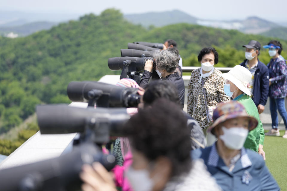 Visitors use binoculars to see the North Korean side from the unification observatory in Paju, South Korea, Thursday, May 12, 2022. North Korea imposed a nationwide lockdown Thursday to control its first acknowledged COVID-19 outbreak after holding for more than two years to a widely doubted claim of a perfect record keeping out the virus that has spread to nearly every place in the world. (AP Photo/Lee Jin-man)