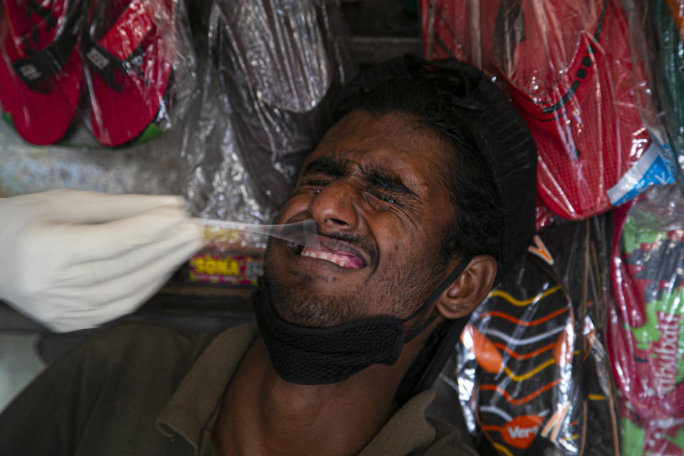 A health worker takes a nasal swab sample of a tailor during random testing for COVID-19 in a market in Gauhati, India, Friday, Oct. 16, 2020. India’s coronavirus fatalities jumped by 895 in the past 24 hours, a day after recording the lowest daily deaths of 680 in nearly three months. The Health Ministry on Friday also reported 63,371 new cases in the past 24 hours, raising India’s total to more than 7.3 million, second in the world behind the U.S. (AP Photo/Anupam Nath)