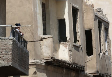 A woman stands in a balcony with old houses in the background at Darb al-Labbana hillside neighbourhood in Cairo