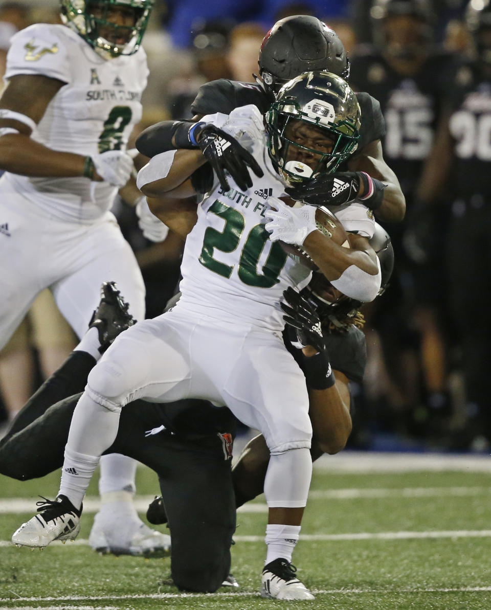 South Florida running back Johnny Ford (20) is tackled by Tulsa safety Manny Bunch, bottom, and safety McKinley Whitfield, top, in the first half of an NCAA college football game in Tulsa, Okla., Friday, Oct. 12, 2018. (AP Photo/Sue Ogrocki)