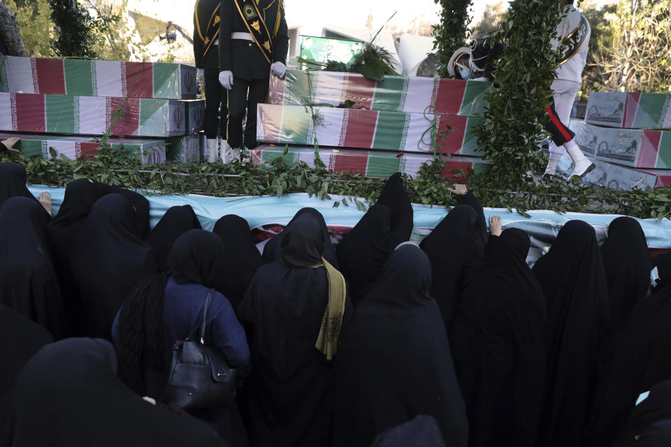 Iranian women mourn next to flag-draped caskets of unknown soldiers who were killed during the 1980-88 Iran-Iraq war, whose remains were recently recovered from former battlefields, during their funeral procession in Tehran, Iran, Thursday, Jan. 6, 2022. Thousands of mourners poured into the streets of Iranian cities on Thursday for the mass funeral of 250 victims of the war, a testament to the brutal conflict's widespread scale and enduring legacy 35 years later. (AP Photo/Vahid Salemi)
