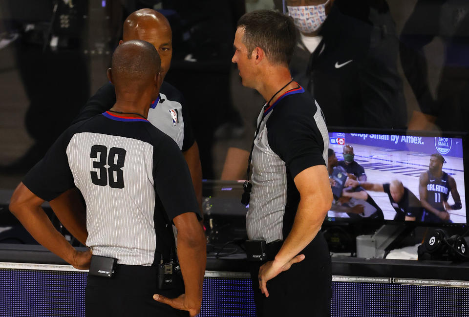 NBA referees huddle to talk about a fight between Orlando Magic's James Ennis III and Milwaukee Bucks' Marvin Williams during Game 3 of an NBA basketball first-round playoff series, Saturday, Aug. 22, 2020, in Lake Buena Vista, Fla. (Mike Ehrmann/Pool Photo via AP)