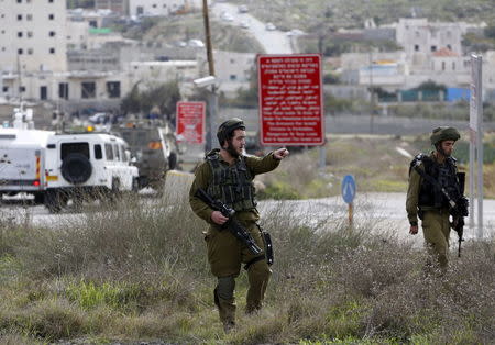 An Israeli soldier gestures as he stands guard near the scene of what the Israeli army said was a suspected Palestinian stabbing attack, near the West Bank Al-Fawwar refugee camp, south of Hebron November 25, 2015. REUTERS/Mussa Qawasma