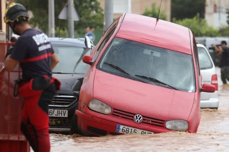 A firefighter stands next to damaged cars after heavy rains in Los Alcazeres