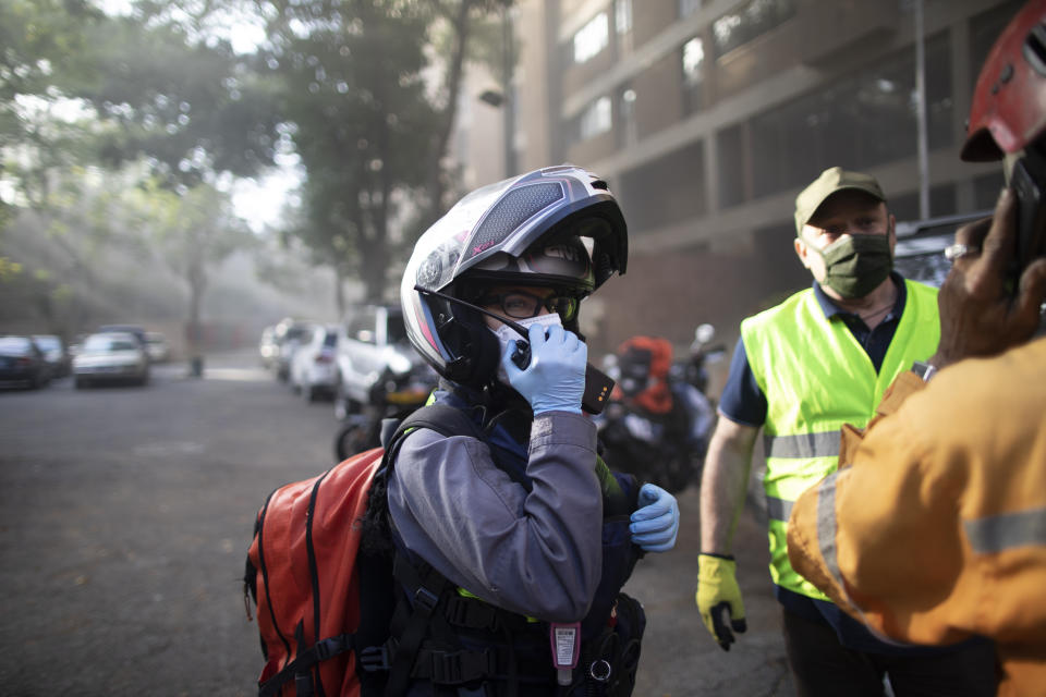 Angels of the Road volunteer paramedic Zully Rodiz speaks on the radio as she arrives to a car fire at a parking lot in Caracas, Venezuela, Monday, Feb. 8, 2021. The volunteers keep a constant ear on walkie-talkie radio traffic and scan online chats dedicated to emergency services. (AP Photo/Ariana Cubillos)