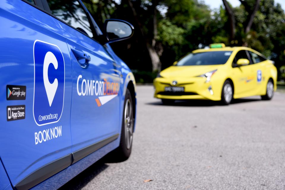 A blue and a yellow ComfortDelGro taxi on the road, illustrating a story on taxi and ride-sharing fare-related changes.