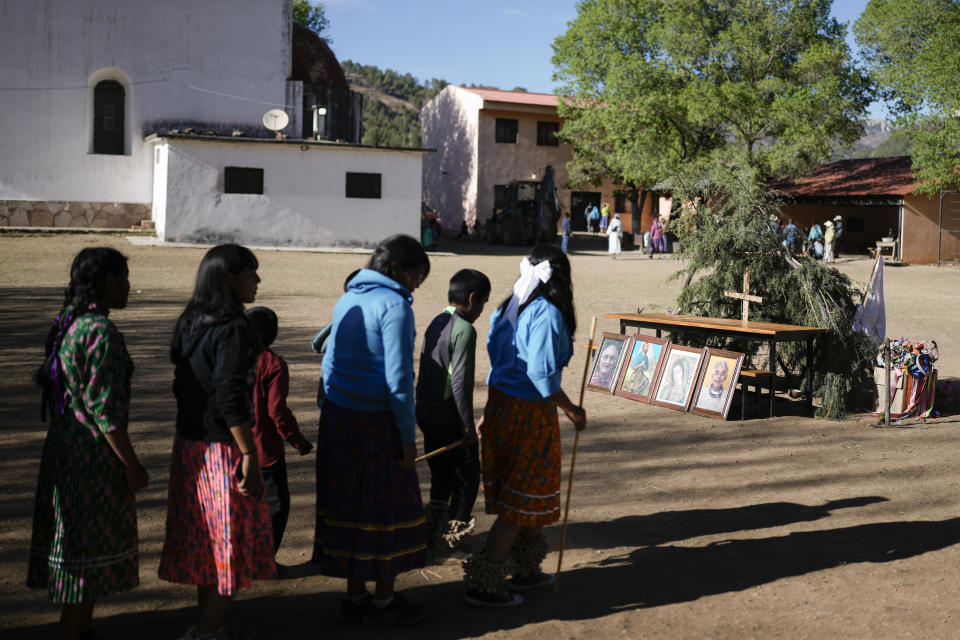 Jóvenes indígenas rarámuri caminan hacia un altar donde hay colocados retratos de dos curas jesuitas muertos, de San Isidro El Labrador y de Nuestra Señora de Guadalupe para la ceremonia sagrada Yúmari para pedir por lluvia y buenas cosechas y en honor de los jesuitas Javier Campos y Joaquín Mora que fueron asesinados en 2022 por el líder de una banda, en Cuiteco, México, el viernes 10 de mayo de 2024. Entre los habitantes de las montañas de Tarahumara, especialmente entre los indígenas rarámuri, los sacerdotes son a menudo percibidos como figuras profundamente queridas que ofrecen ayuda. (AP Foto/Eduardo Verdugo)