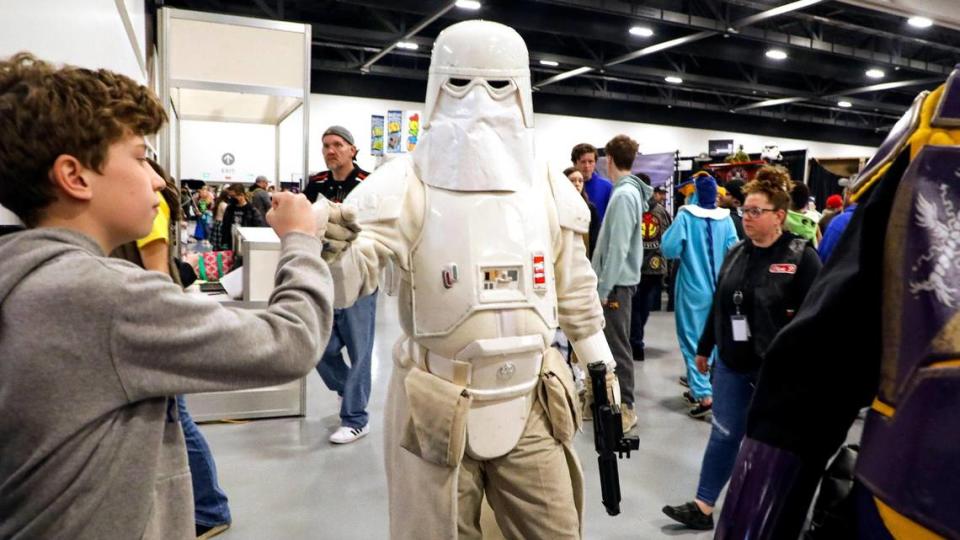 A patron in cosplay as a snowtrooper from the Star Wars franchise greets a fan at the Lexington Comic and Toy Convention at the Central Bank Center in Lexington, Ky. on Sunday, March 27, 2022. Costumes are allowed and cosplay is encouraged at convention.