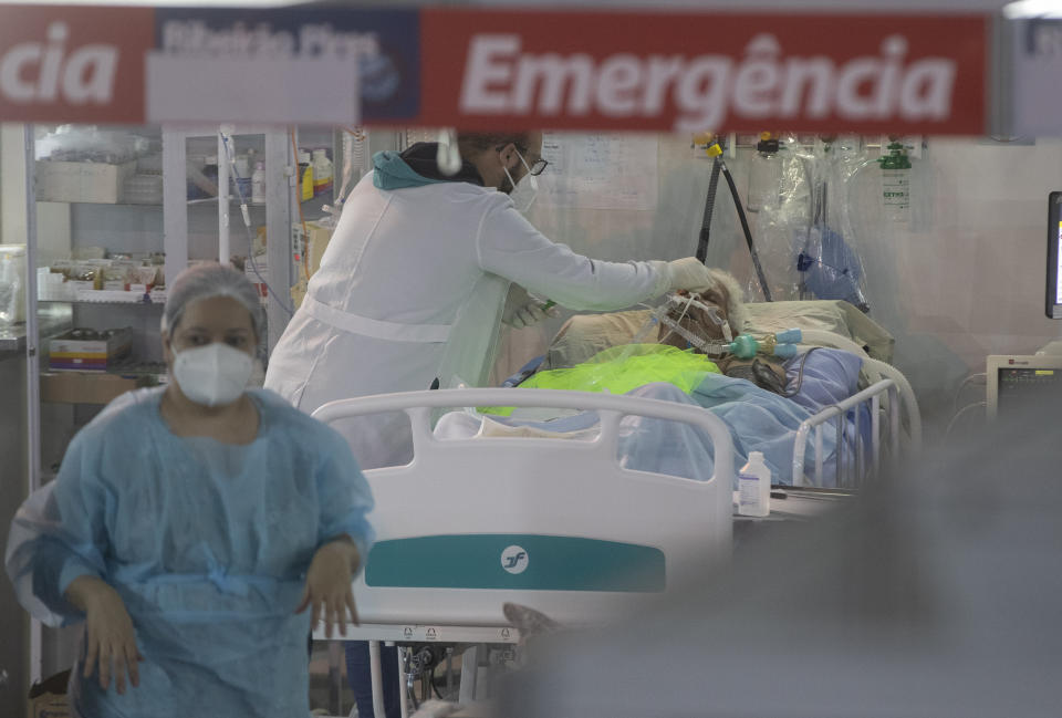 Health workers treat a COVID-19 patient at the emergency unit of a field hospital set up to treat COVID patients in Ribeirao Pires, greater Sao Paulo area, Brazil, Tuesday, April 13, 2021. (AP Photo/Andre Penner)