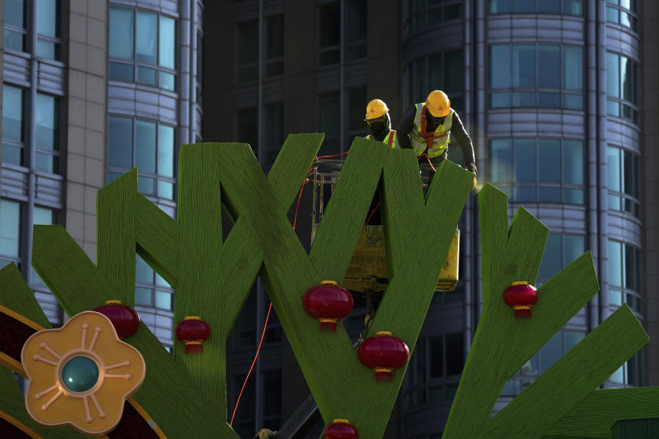 Workers color Chinese Lunar New Year decorations near a commercial office building in Beijing on Sunday, Jan. 16, 2022. China’s economy expanded by 8.1% in 2021 but Beijing faces pressure to shore up activity after an abrupt slump in the second half as the ruling Communist Party forced its vast real estate industry to cut surging debt. (AP Photo/Andy Wong)