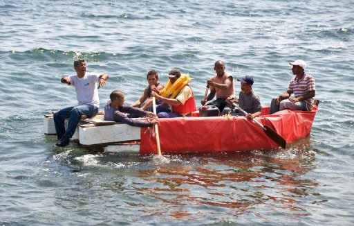 Once hombres de entre 25 y 45 años encallaron su embarcación en la orilla de la turística playa de Hollywood, al norte de Miami, este lunes, donde descendieron besando la arena de alegría y fueron auxiliados por los bañistas, al confirmar que venían de Cuba. (AFP | Adalberto Roque)