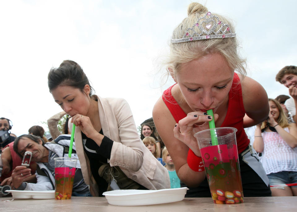 BERLIN, GERMANY - JULY 21: Contestants compete in an event in which they must suck candy out of a cup of the ubiquitous Berlin drink bubble tea during the second annual Hipster Olympics on July 21, 2012 in Berlin, Germany. With events such as the "Horn-Rimmed Glasses Throw," "Skinny Jeans Tug-O-War," "Vinyl Record Spinning Contest" and "Cloth Tote Sack Race," the Hipster Olympics both mocks and celebrates the Hipster subculture, which some critics claim could never be accurately defined and others that it never existed in the first place. The imprecise nature of determining what makes one a member means that the symptomatic elements of adherants to the group vary in each country, but the archetype of the version in Berlin, one of the more popular locations for those following its lifestyle, along with London and Brooklyn, includes a penchant for canvas tote bags, the carbonated yerba mate drink Club Mate, analogue film cameras, asymmetrical haircuts, 80s neon fashion, and, allegedly, a heavy dose of irony. To some in Berlin, members of the hipster "movement" have replaced a former unwanted identity in gentrifying neighborhoods, the Yuppie, for targets of criticism, as landlords raise rents in the areas to which they relocate, particularly the up-and-coming neighborhood of Neukoelln. (Photo by Adam Berry/Getty Images)