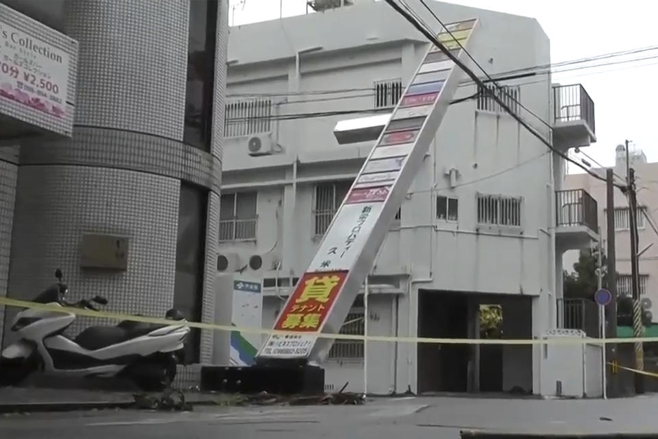 This image made from video provided by NTV shows tilted shop sign, following Typhoon Khanun, in Naha, Okinawa prefecture, Aug. 3, 2023. The typhoon that damaged homes and knocked out power on Okinawa and other southern Japanese islands this week was slowly moving west Thursday but is forecast to make a U-turn and dump even more rain on the archipelago.(NTV via AP)