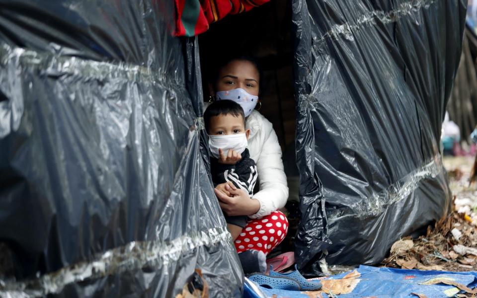 Venezuelan citizens remain in a makeshift camp set on the separator of the northern highway, in Bogota, Colombia - Mauricio Duenas Castaneda/Shutterstock