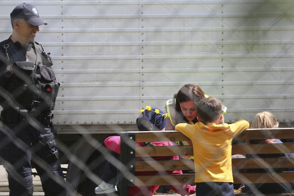 A police officer plays with a group of children inside a detention center where authorities have brought back from Syria 110 Kosovar citizens, mostly women and children in the village of Vranidol on Sunday, April 20, 2019. Four suspected fighters have been arrested, but other returnees will be cared for, before being sent to homes over the coming days, according to Justice Minister Abelard Tahiri.(AP Photo/Visar Kryeziu)