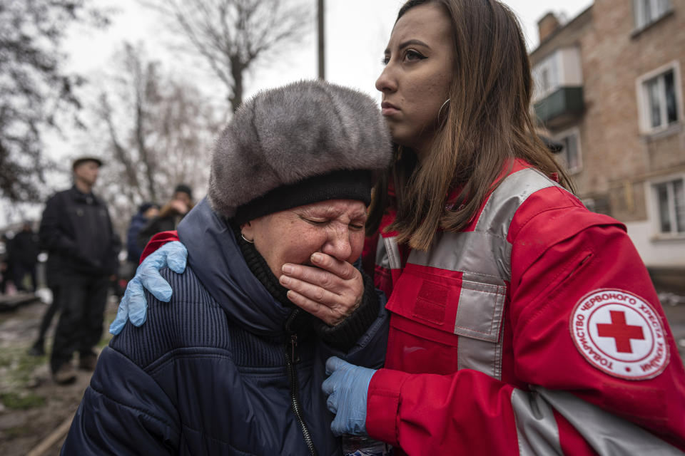 A woman cries in front of the building which was destroyed by a Russian attack in Kryvyi Rih, Ukraine, Friday, Dec. 16, 2022. Russian forces launched at least 60 missiles across Ukraine on Friday, officials said, reporting explosions in at least four cities, including Kyiv. At least two people were killed by a strike on a residential building in central Ukraine, where a hunt was on for survivors. (AP Photo/Evgeniy Maloletka)