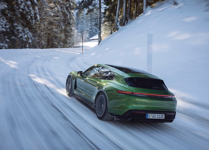 A Porsche Taycan Turbo S Sport Turismo in green driving on a snowy road