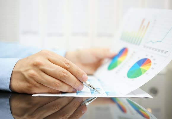 Hands pointing to charts on a piece of paper