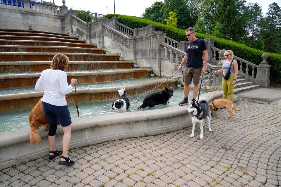 From left: Kim Walting, Eric Humbert and Elyssa Veite gather with an assortment of dogs around Ault Park’s cascading fountain on Thursday, July 20, 2023, in Cincinnati. The fountain requires $2 million in upkeep.