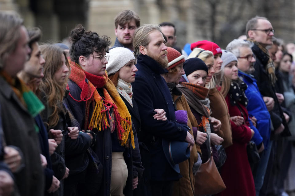 People stand as a human chain to honor victims of mass shooting in front of the building of Philosophical Faculty of Charles University in Prague, Czech Republic, Thursday, Jan. 4, 2024. Thousands of students and other Czechs marched in silence in the Czech capital on Thursday to honor the victims of the country's worst mass killing that left 14 dead on Dec. 21, 2023.(AP Photo/Petr David Josek)