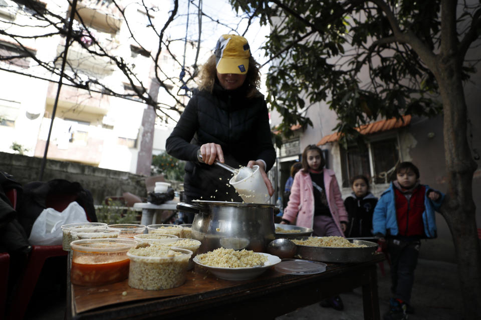 A woman cooks and serves food to displaced people following a devastating earthquake, at her house in the coastal city of Latakia, Syria, Friday, Feb. 10, 2023. The 7.8 magnitude earthquake that hit Turkey and Syria, killing more than 23,000 this week has displaced millions of people in war-torn Syria. The country's 12-year-old uprising turned civil war had already displaced half the country's pre-war population of 23 million before the earthquake. (AP Photo/Omar Sanadiki)