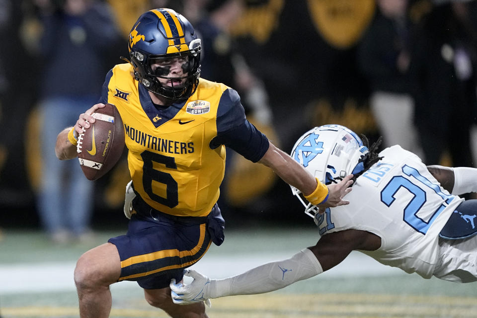 FILE - West Virginia quarterback Garrett Greene runs past North Carolina defensive back Kaleb Cost during the first half of an NCAA college football game at the Duke's Mayo Bowl Wednesday, Dec. 27, 2023, in Charlotte, N.C. As a junior Greene emerged as a solid dual threat in his first full season as a starter. (AP Photo/Chris Carlson, File)