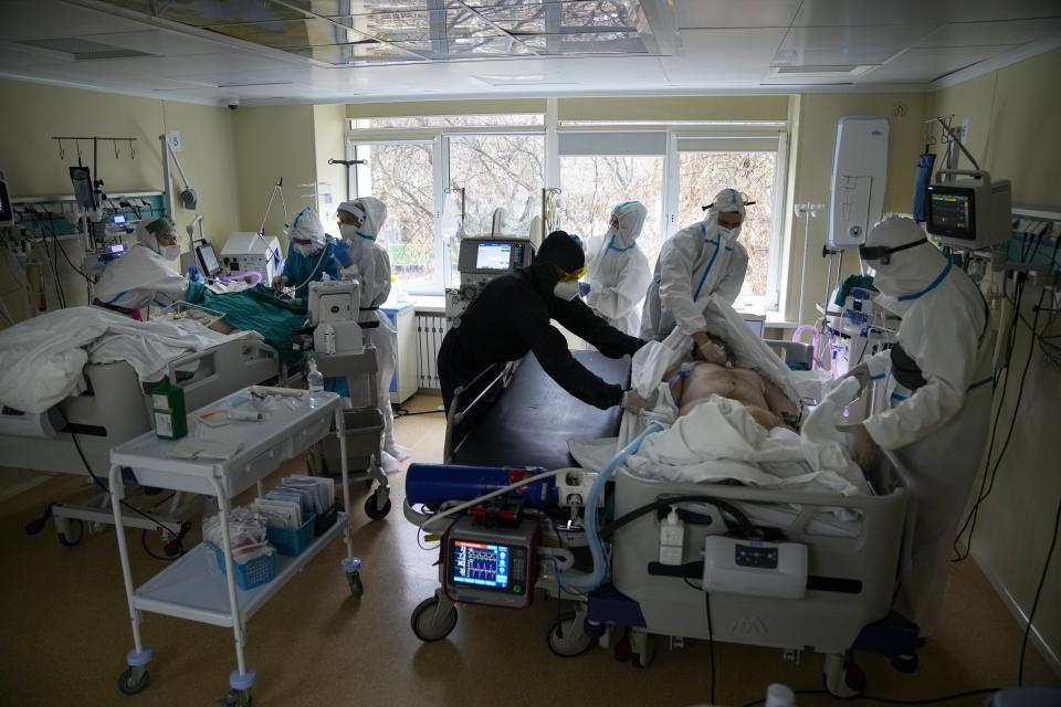 Medics wearing special suits to protect against coronavirus treat a patient with coronavirus, left, as others prepare a patent to move at an ICU at the Moscow City Clinical Hospital 52, in Moscow, Russia, Tuesday, Oct. 19, 2021. Russia hit another daily record of coronavirus deaths Tuesday as rapidly surging infection rates raised pressure on the country's health care system and prompted the government to suggest declaring a nonworking week. (AP Photo/Alexander Zemlianichenko)