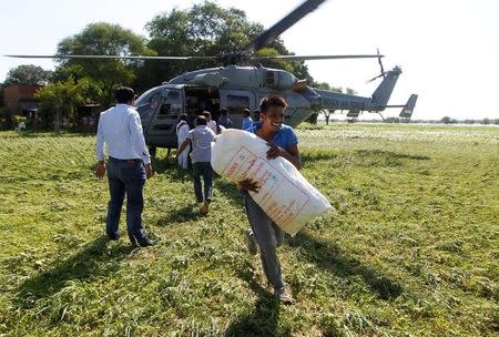 A man unloads relief food material from an Indian Air Force helicopter to be distributed among the flood victims, on the outskirts of Allahabad, India, August 24, 2016. REUTERS/Jitendra Prakash