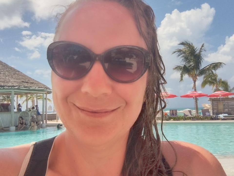 A woman wearing sunglasses taking a selfie in a pool.