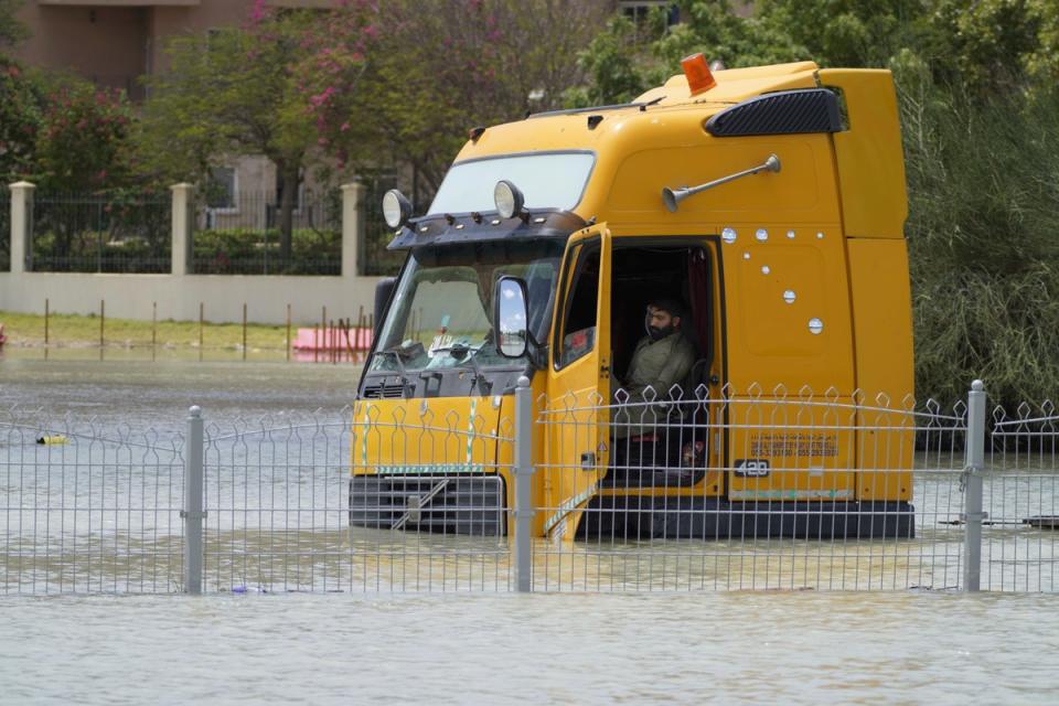 A man sits in a semitruck stuck in floodwater in Dubai, United Arab Emirates, Wednesday, April 17, 2024 (AP)