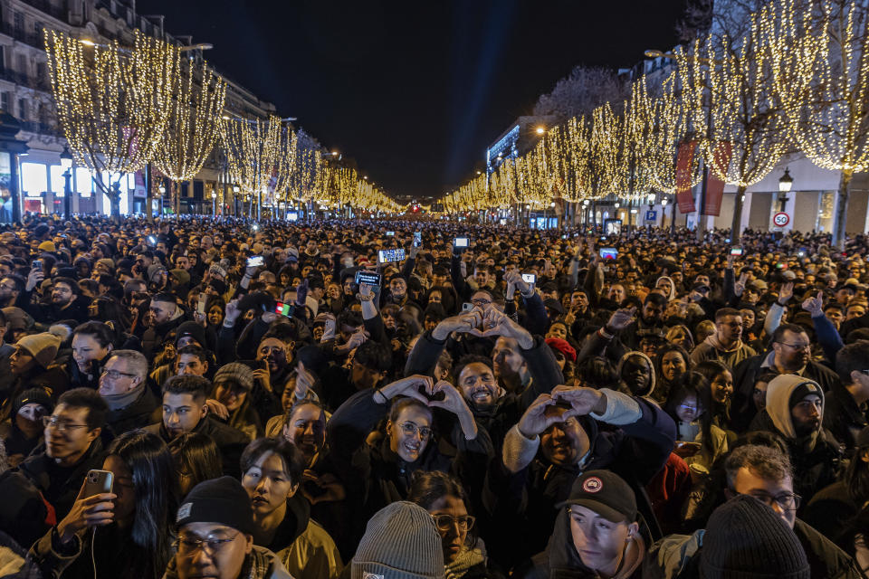 People watch a light show projected on the Arc de Triomphe as they celebrate New Year's on the Champs Elysees in Paris, France, Sunday, Dec. 31, 2023. (AP Photo/Aurelien Morissard)