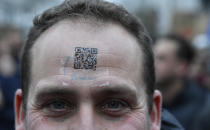 A protestor wears a QR code on his forehead during a demonstration against COVID-19 measures in Brussels, Sunday, Jan. 23, 2022. Demonstrators gathered in the Belgian capital to protest what they regard as overly extreme measures by the government to fight the COVID-19 pandemic, including a vaccine pass regulating access to certain places and activities and possible compulsory vaccines.(AP Photo/Geert Vanden Wijngaert)