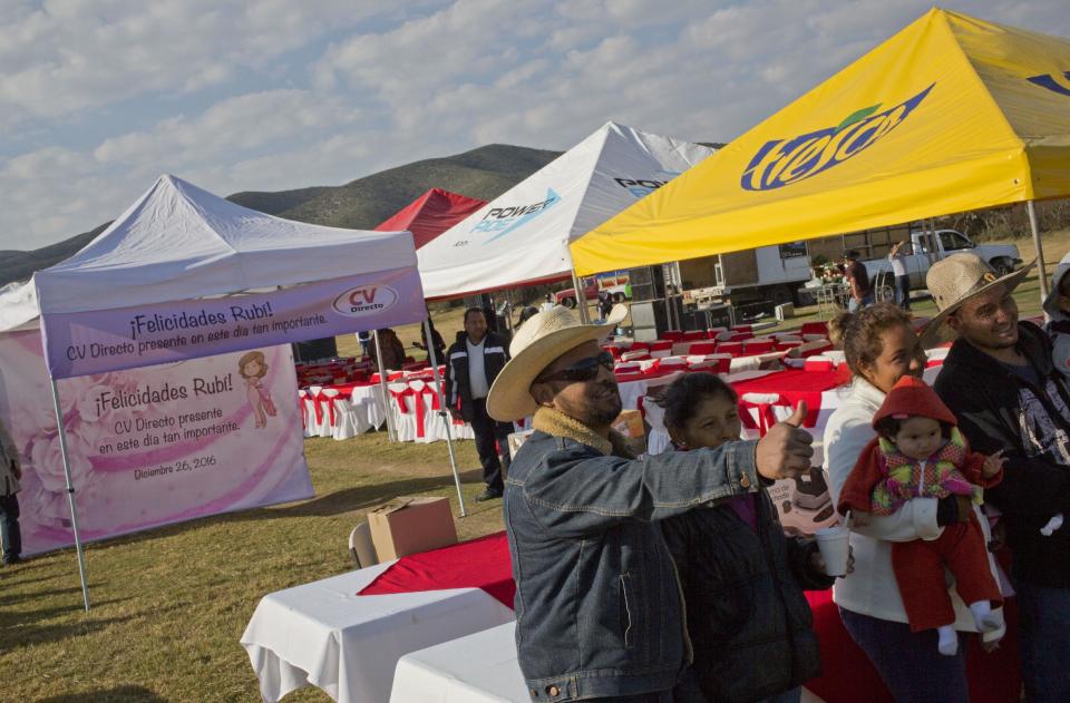 Visitors pose for souvenir pictures at the site of a Mass that is part of Rubi Ibarra's down-home 15th birthday party in the of La Joya, San Luis Potosi State, Mexico, Monday, Dec. 26, 2016. Millions of people responded to the invitation for Rubi's Dec. 26th coming of age party in rural northern Mexico, after her parent's video asking "everybody" to attend went viral. (AP Photo/Enric Marti)