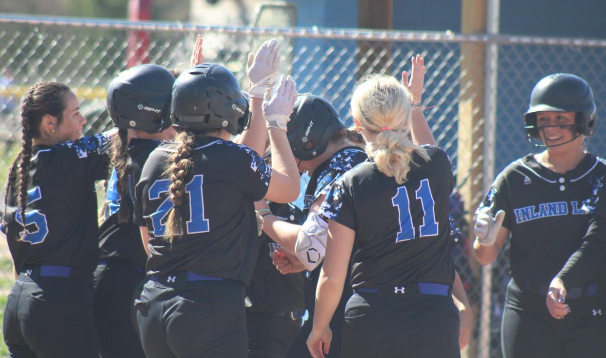 Inland Lakes’ softball players celebrate at home plate with senior Maggie Grant (19), who blasted a 3-run homer during a game one victory over Mancelona on Friday.