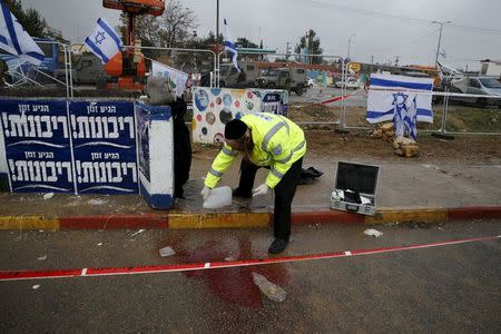 Zaka emergency personnel clean a bloodstain from the ground at the scene where Israeli security forces shot dead a Palestinian assailant who tried to stab a man at Gush Etzion junction near a West Bank settlement on Tuesday, police said, a location that has seen many attacks during two months of violence, December 1, 2015. REUTERS/Baz Ratner