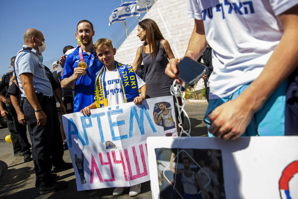 CORRECTS NAME TO ARTEM DOLGOPYAT - Artem Dolgopyat, Israel's artistic gymnastics men's gold medalist of Tokyo 2020, holds his medal on his arrival to Ben Gurion Airport near Tel Aviv, Israel, Tuesday Aug. 3, 2021. The Ukrainian-born Israeli gymnast was hailed as a national hero for winning Israel's second-ever gold medal — and its first in artistic gymnastics. But the celebrations were tempered after his mother lamented that the country's authorities will not allow him to wed because he is not considered Jewish according to Orthodox law. (AP Photo/Ariel Schalit)