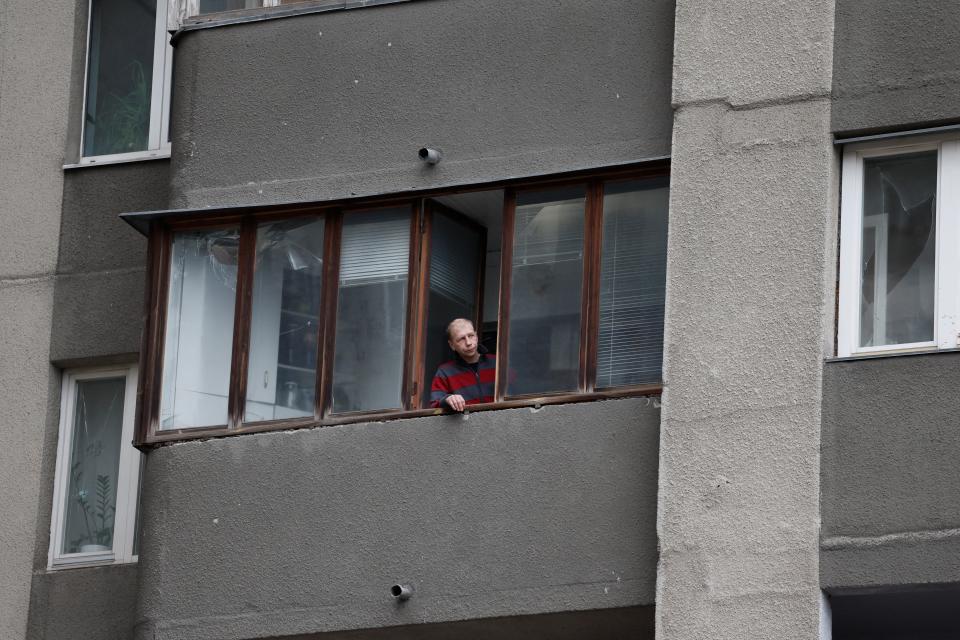 A person looks out alongside damaged windows in Kyiv at the site of a Russian missile strike after a flurry of attacks on the war-hit country today (Reuters)