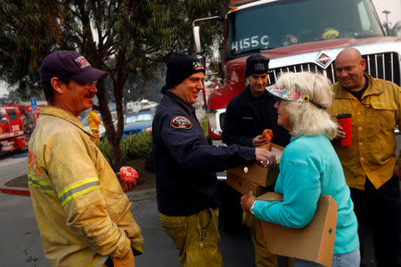 A La Conchita resident gives donuts to Sacramento County firefighters taking a break from fighting wildfires during the Thomas fire in Carpinteria, California, U.S. December 12, 2017. REUTERS/Patrick T Fallon