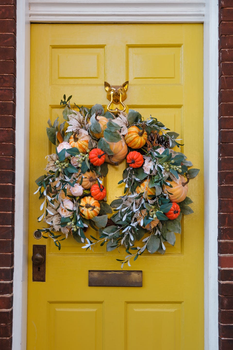 close up of autumn wreath adorning yellow front door