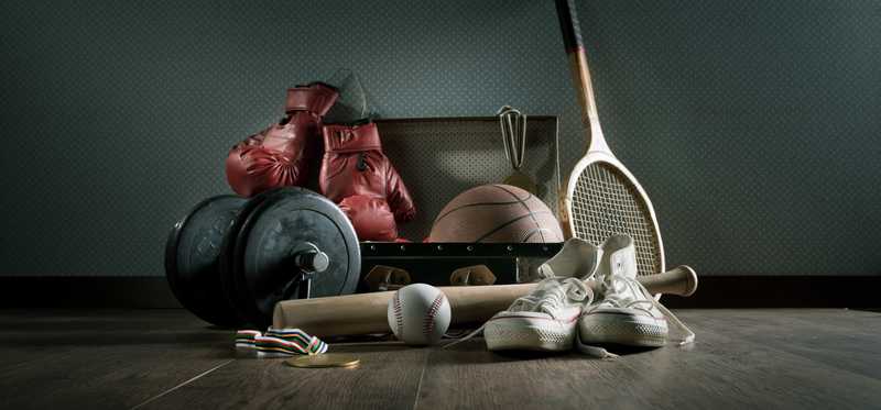 A variety of sporting equipment on the floor in a darkened room.